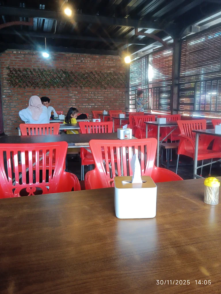 Interior Kedai Bambu Merah dengan dinding bata, kursi merah, dan suasana hangat